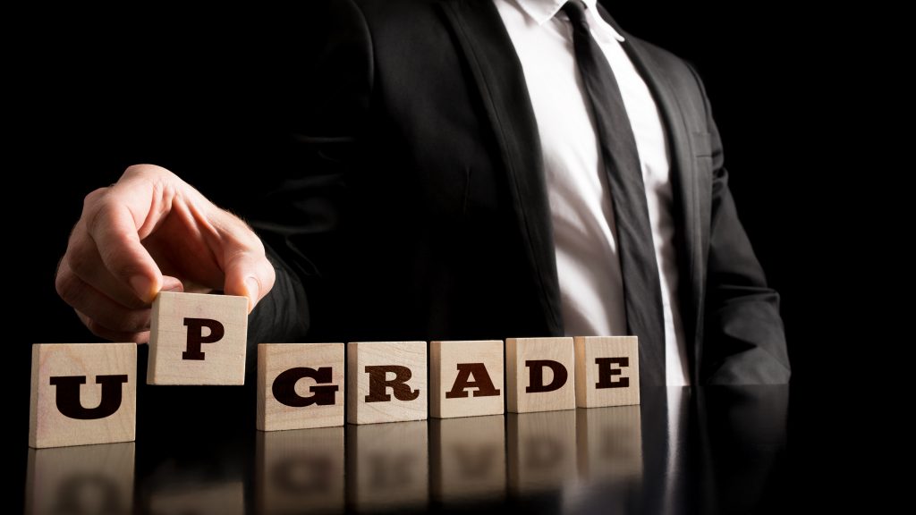 Close up Businessman Arranging Wooden Blocks with Letters Forming Conceptual Upgrade Word.