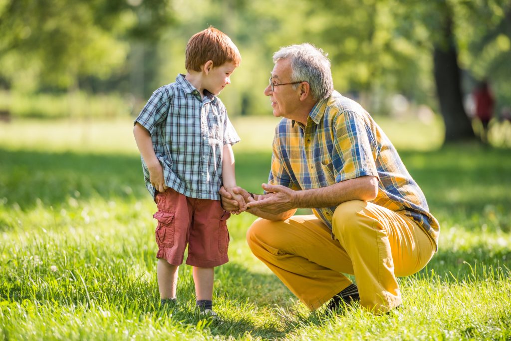 Grandfather and grandson talking in park