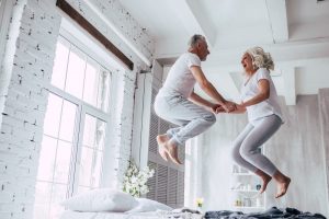 Image of senior couple jumping on the bed to celebrate their windfall