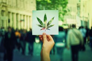 Image of a marijuana leaf silhouette held over a city street