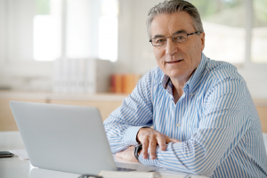 Image of a proud senior man sitting and using his computer