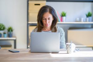 Image of a skeptical middle aged women looking at her laptop screen