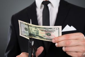 Image of a businessman cutting a $50 bill with scissors