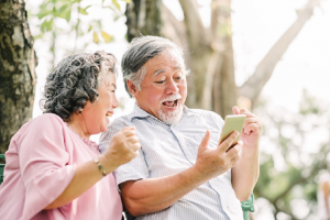 Image of a happy senior couple tracking their retirement income on a smartphone