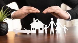 Image of hands over a family and their assets, representing an insurance policy