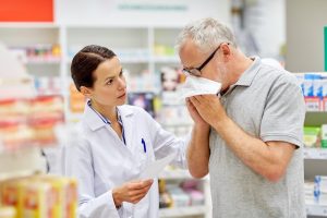 Image of a senior man blowing his nose at a pharmacy