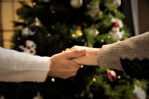 Image of two seniors holding hands in front of a Christmas tree