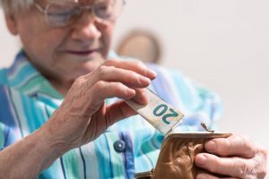 Image of a senior woman saving a banknote in her purse