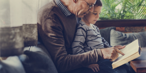 Image of a grandfather reading to his grandson