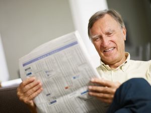 Image of a happy senior reading the stock listings for the energy sector