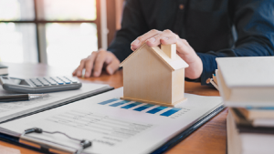 Image of a model house over a set of data, representing a real estate investment trust portfolio