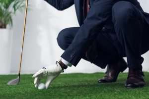 Image of a businessman playing golf in his office