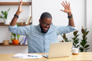 Image of a happy investor celebrating over his laptop