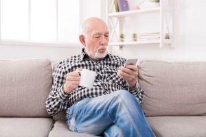 Image of a man sitting on a couch watching microcap stock movements on his phone