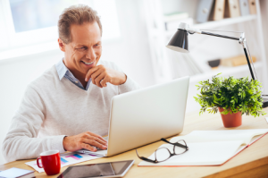 Image of a satisfied senior man looking at his laptop