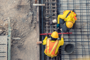 Image of two construction workers at work measuring metal