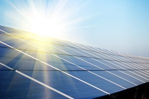 Image of the sun shining over a set of solar panels