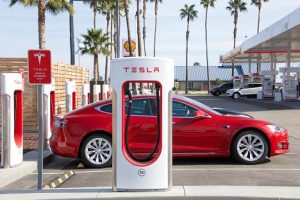 Image of a red Tesla sedan at a charging station