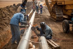 Image of pipeline workers welding a pipeline’s outer casing