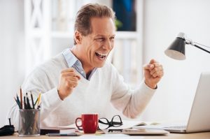 Image of a middle-aged man celebrating at his computer