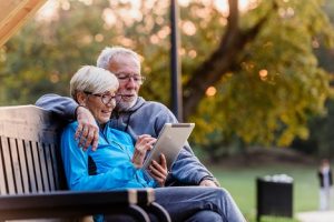 Image of a senior couple out in nature looking at a tablet