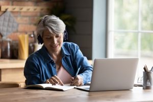 Image of a senior woman taking notes from her laptop