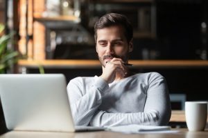 Image of a thoughtful young man using his laptop