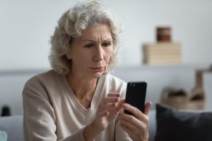 Image of a confused senior looking at her phone