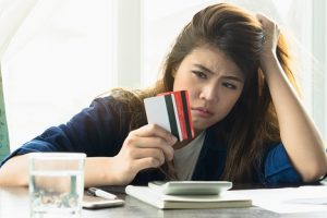 Image of a stressed young woman holding two credit cards