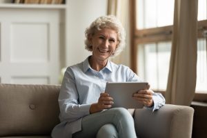 Image of a pleased senior woman looking at a tablet