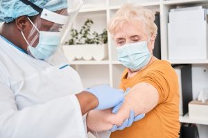 Image of a doctor vaccinating an elderly woman