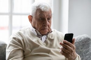 Image of a surprised senior man looking at his phone