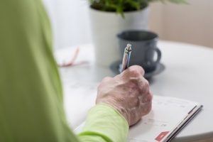 Image of a senior woman’s hand writing a note in her calendar