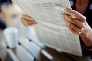 Image of a senior woman holding a newspaper