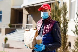 Image of a food courier in a protective mask and gloves