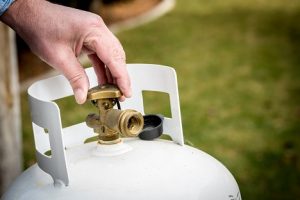 Image of a hand adjusting the valve on a propane tank