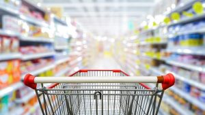 Image of a red shopping cart in the middle of a supermarket aisle