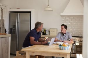 Image of a father and his son talking while seated in the kitchen