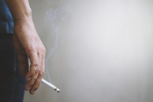 Image of a hand holding a lit cigarette