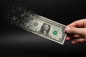 Image of a dollar disintegrating against a black background, representing inflation