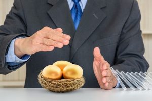 Investor protecting three golden eggs, which represent his nest egg