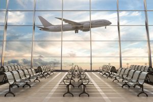 Image of an airport terminal lounge with a plane taking off outside