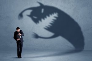 Image of a businessman cowering from a large monster looming from his shadow