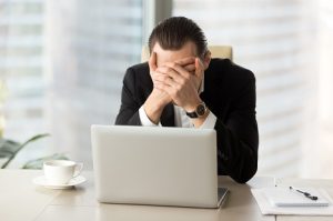 Image of a distraught businessman covering his face