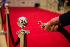 Image of a hand unlinking a velvet rope barrier