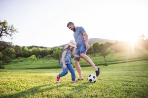 Image of a father and daughter playing soccer