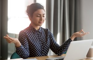 Image of a woman meditating in front of her computer