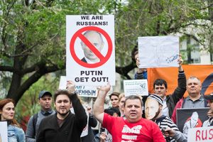 Protestors holding a sign that reads “We are Russians! Putin, get out!”