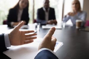 Hands of a business leader at a conference table with employees