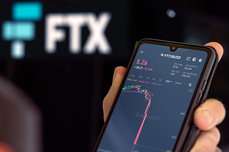 Hand holding phone looking at stock chart of FTX